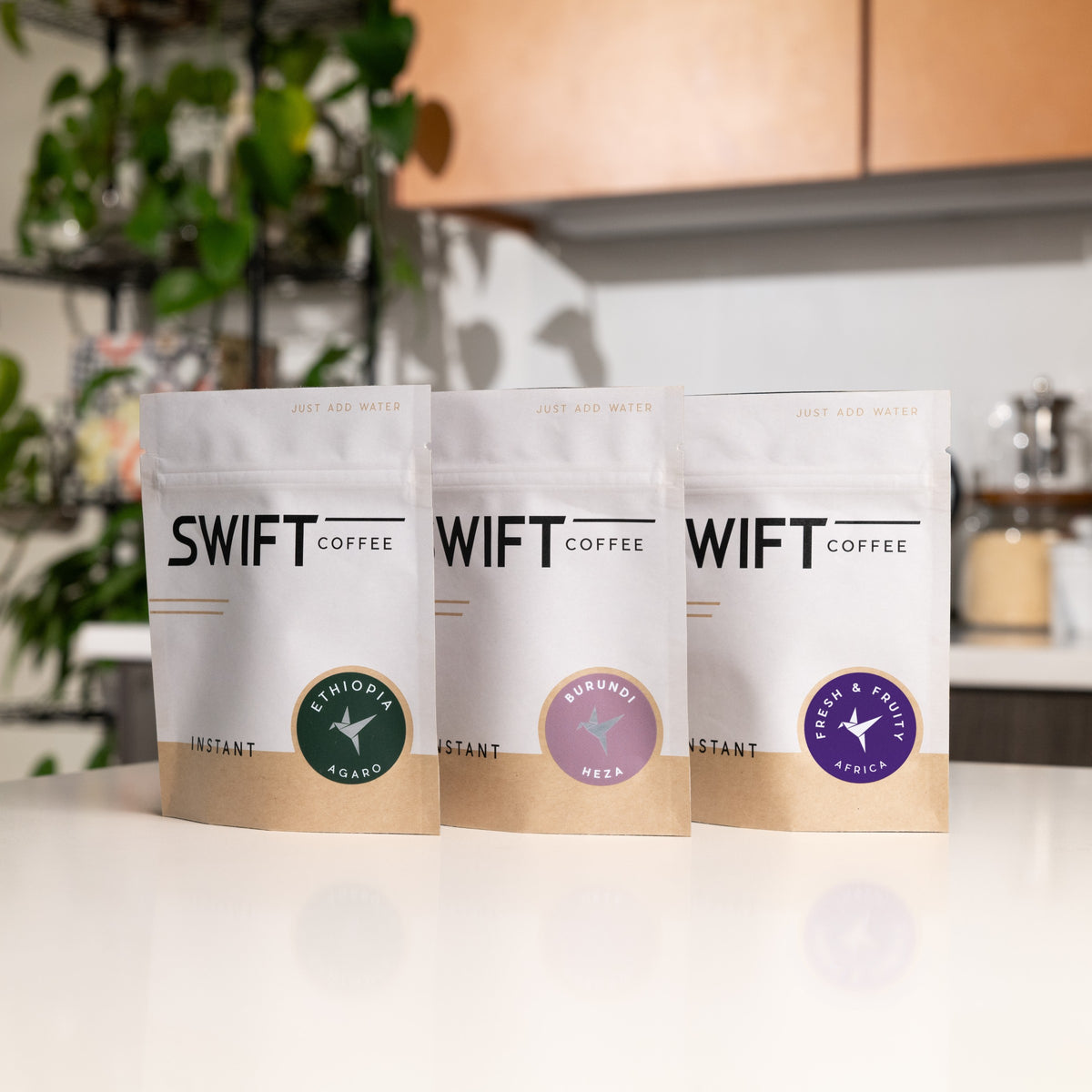 Swift Coffee East Africa Trio on a kitchen counter: Ethiopia Agaro, Burundi Heza and Fresh & Fruity Africa instant coffee pouches