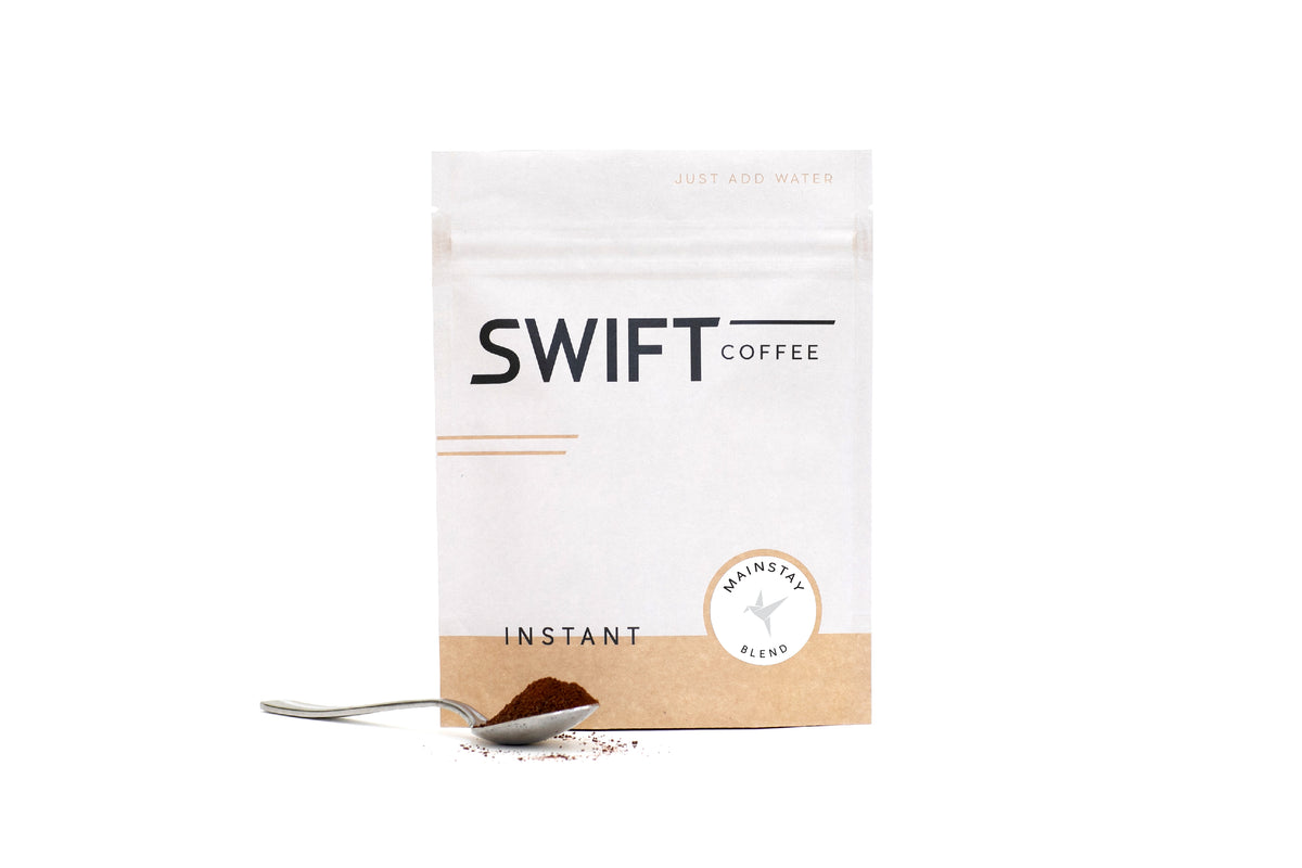 Swift Coffee Mainstay Blend instant coffee pouch with a spoonful of instant coffee, on a white background