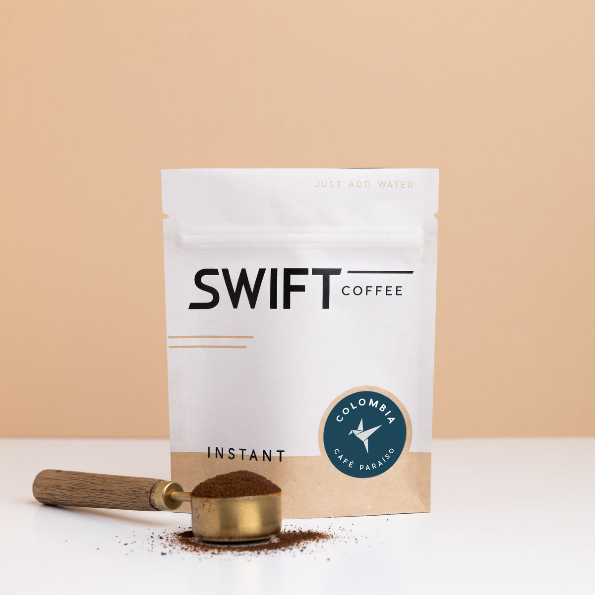 Swift Coffee Colombia Cafe Paraiso instant coffee pouch with a brass scoop of instant coffee in front