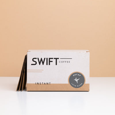 Box of Swift Coffee Decaf Latin Blend instant coffee with single-serve sachets leaning behind it