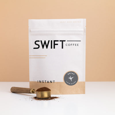 Swift Coffee Decaf Latin Blend instant coffee pouch with a brass scoop of instant coffee in front