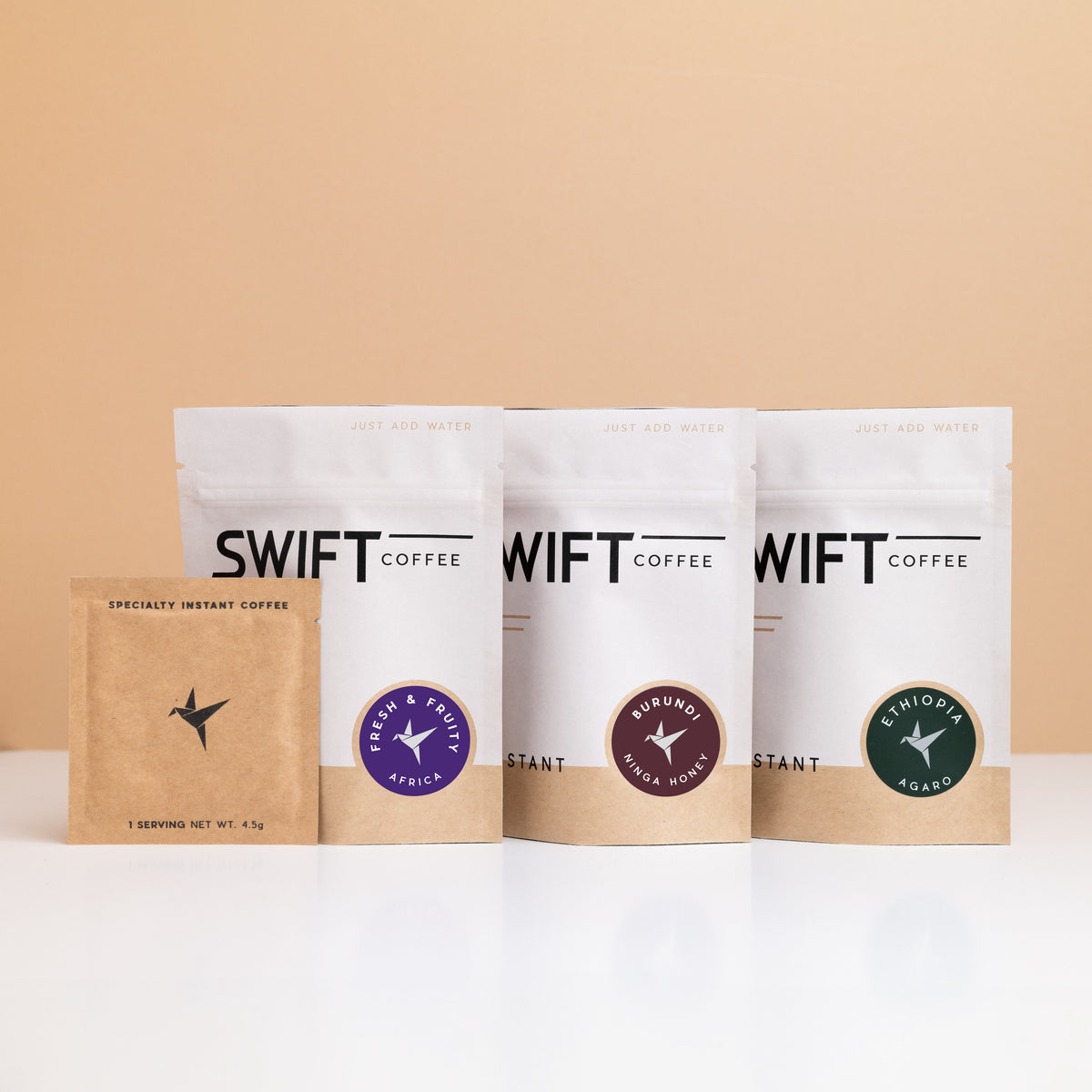 Three Swift Coffee pouches from the East Africa Trio with a kraft single-serve sachet