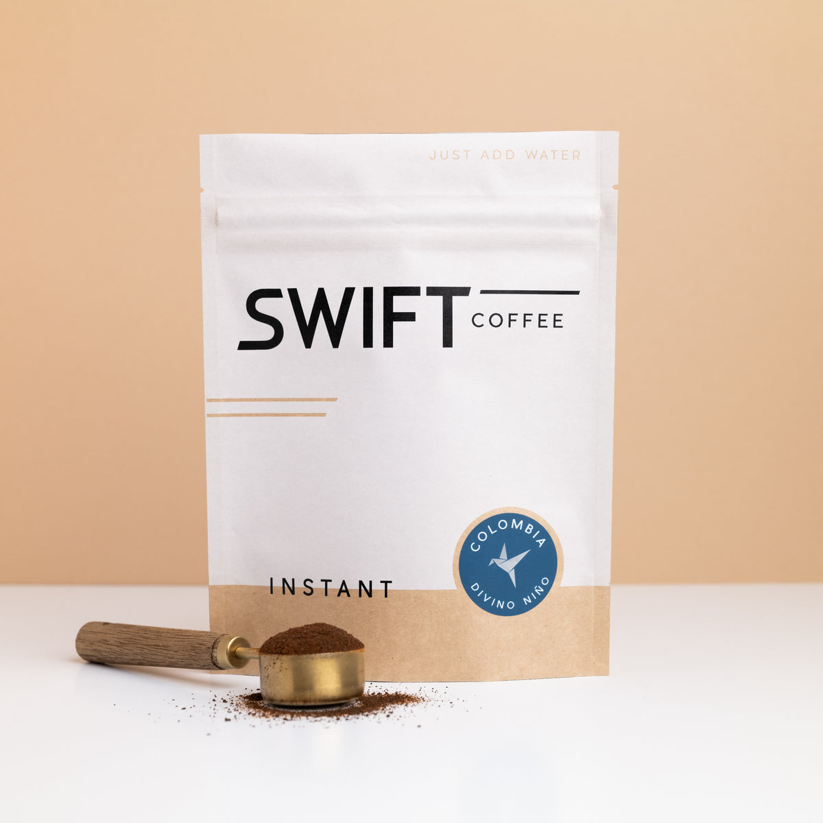 Swift Coffee Colombia Divino Nino instant coffee bulk pouch with a brass scoop of instant coffee in front