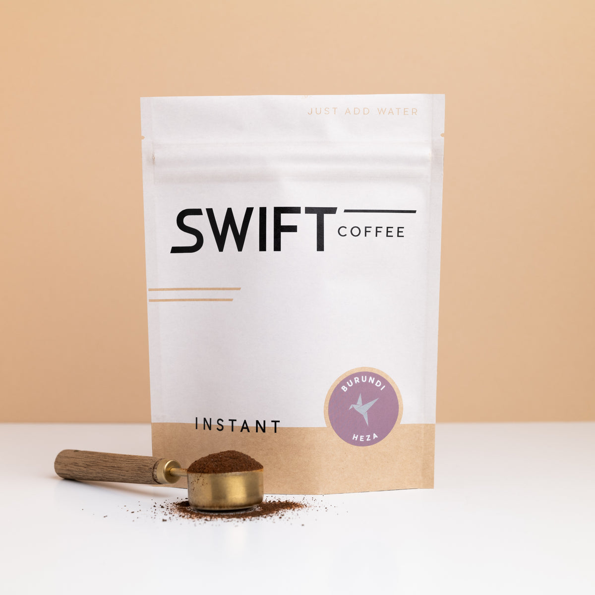 Swift Coffee Burundi Heza instant coffee bulk pouch with a brass scoop of instant coffee in front