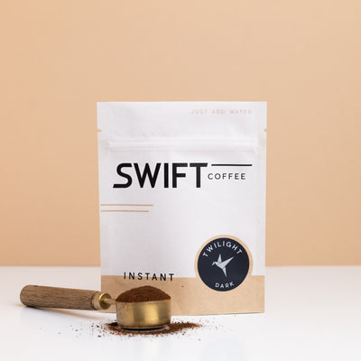Swift Coffee Twilight Dark Roast instant coffee bulk pouch with a brass scoop of instant coffee in front