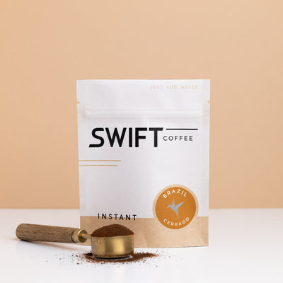 Swift Coffee Brazil Cerrado instant coffee bulk pouch with a brass scoop of instant coffee in front