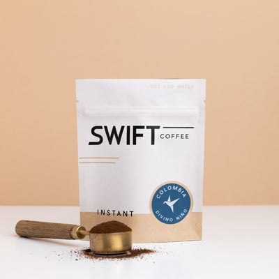 Swift Coffee Colombia Divino Nino instant coffee bulk pouch with a brass scoop of instant coffee in front