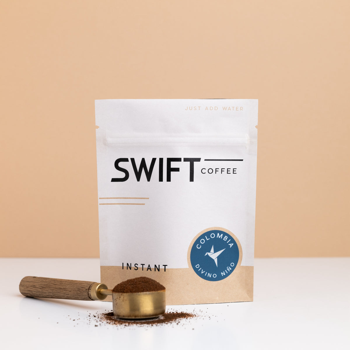 Swift Coffee Colombia Divino Nino instant coffee bulk pouch with a brass scoop of instant coffee in front