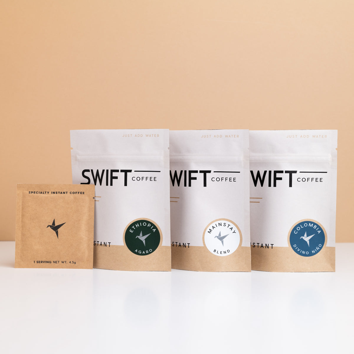 Three Swift Coffee pouches from The Essentials set (Mainstay Blend, Ethiopia Agaro and Colombia) with a kraft single-serve sachet
