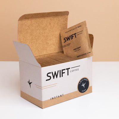 Open box of Swift Coffee Twilight Dark Roast instant coffee single-serve sachets with one sachet propped on top