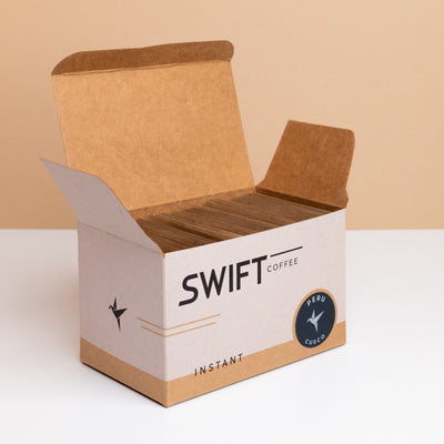 Open box of Swift Coffee Peru Cusco instant coffee, filled with kraft single-serve sachets