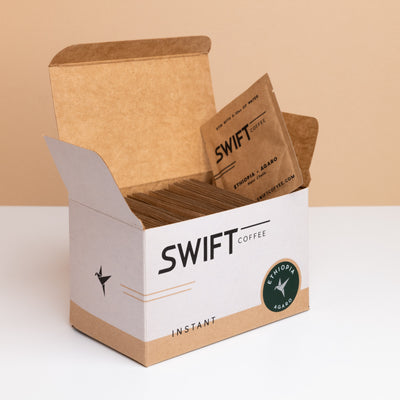 Open box of Swift Coffee Ethiopia Agaro instant coffee single-serve sachets with one sachet propped on top