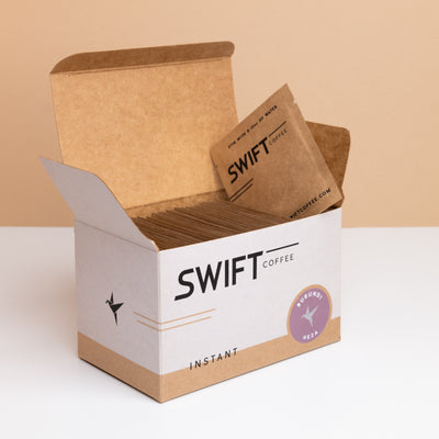 Open box of Swift Coffee Burundi Heza instant coffee single-serve sachets with one sachet propped on top