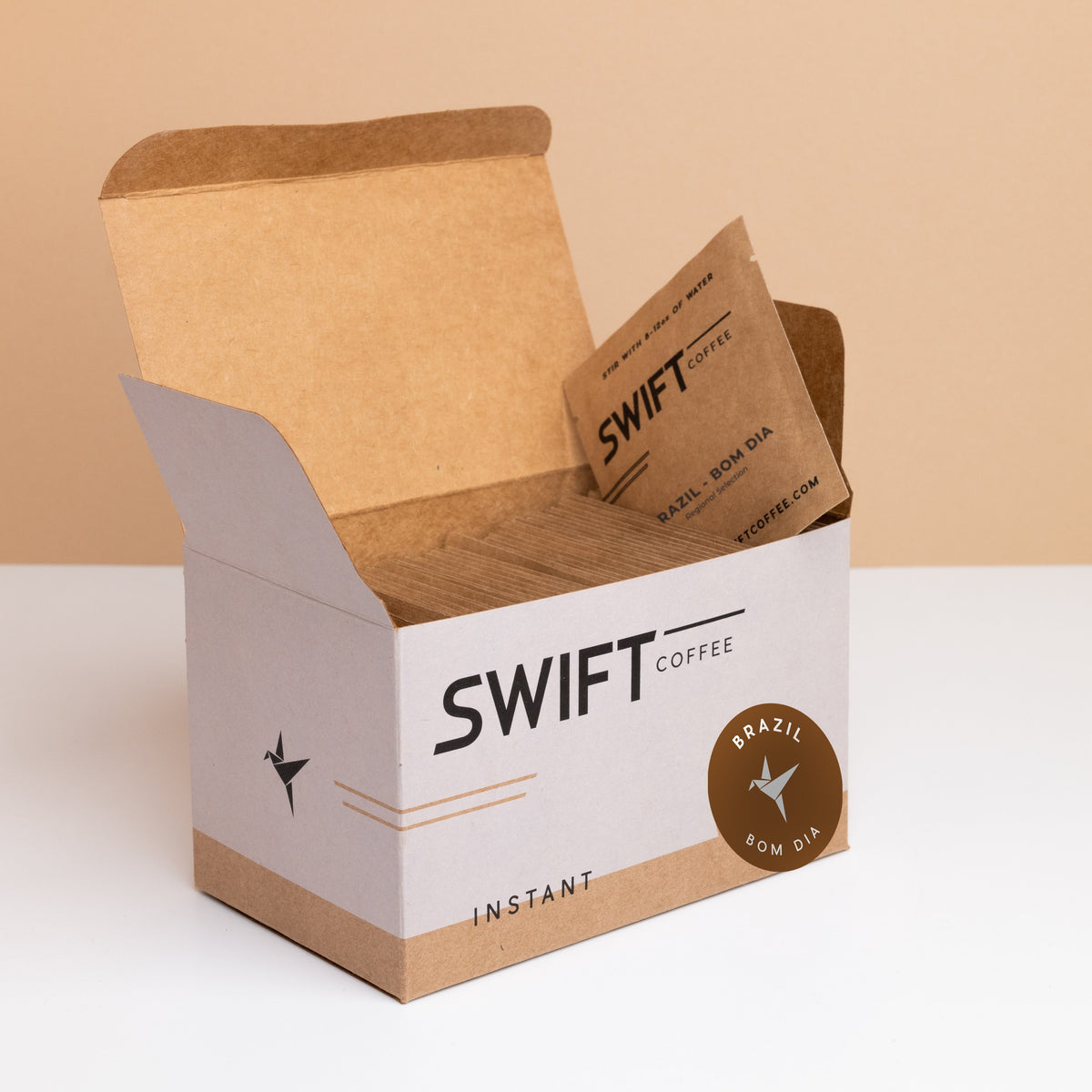 Open box of Swift Coffee Brazil Bom Dia instant coffee single-serve sachets with one sachet propped on top