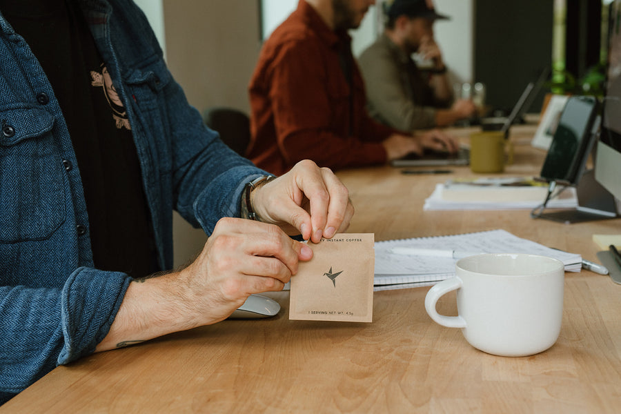 Opening a Swift coffee sachet at a desk