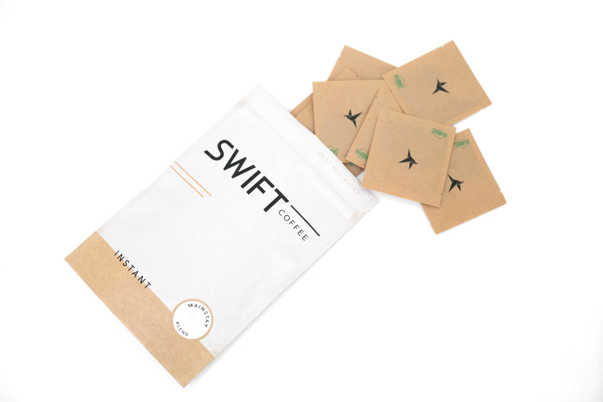 Swift Coffee Mainstay Blend instant coffee pouch lying on its side with kraft single-serve sachets spilling out